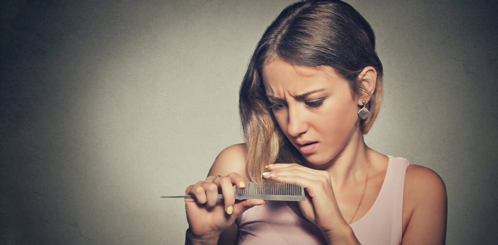Woman noticing hair shedding on her brush.
