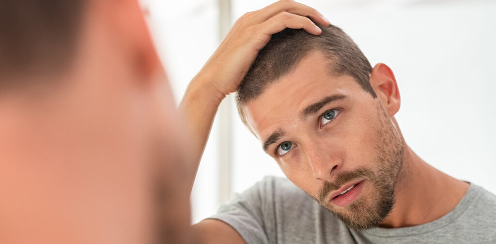 Man looking at hair in the mirror